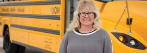 Terri Johnson, bus driver for Schmitty & Sons Bus Company, standing in front of the new all-electric school bus