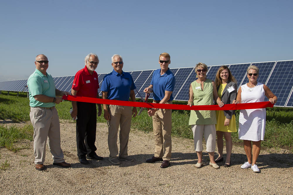 peopel cutting a ribbon at a solar panel site