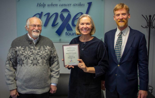 three people holding plaque