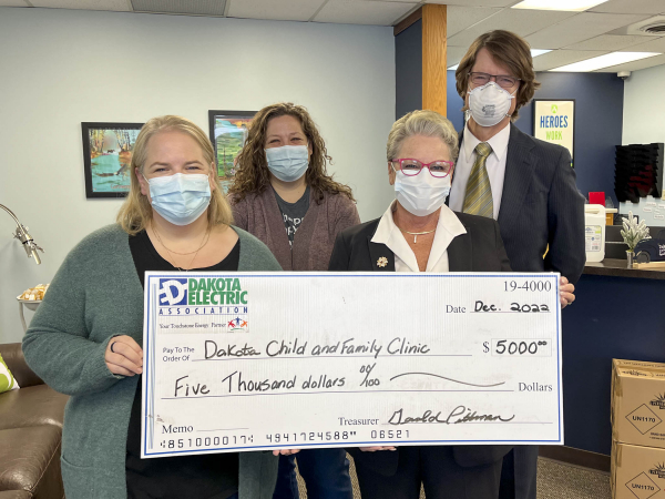 four people holding large check